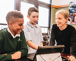 Two middle school students work with their teacher.